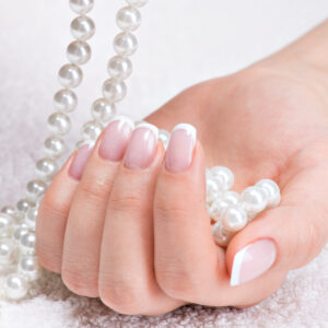 Beautiful woman's nails with beautiful french manicure  and white pearls